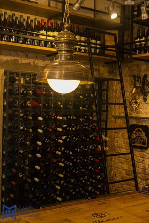 uma luz no teto ao lado de uma prateleira com garrafas de vinho